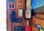 Wood-paneled boat wall with a dense cluster of electrical switches, gauges, a radio, and control panels.