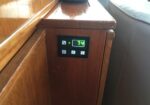 Digital thermostat on a wooden cabinet showing 74°F with control buttons beneath it