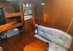 Wood-paneled ship cabin with vintage control panel, meters, and switches alongside a coiled microphone and cords.",