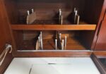 Interior of a wooden cabinet with metal shelf pins and adjustable wooden dividers