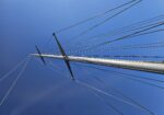 Sailboat mast with rigging cables against a clear blue sky