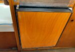 Wooden cabinet door with a black metal frame and small latch, set in a wooden interior