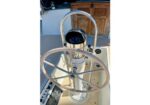 Boat steering wheel mounted on a pedestal in a sailboat cockpit, with a compass behind it