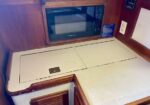 Boat galley with a built-in microwave and folding countertop sections along wood-paneled cabinets.