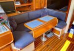 Yacht interior: L-shaped blue cushioned seating around a wooden table with two blue placemats.