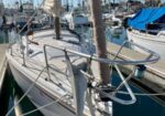 White sailboat moored in a marina with rigging, masts, and blue sky around it.