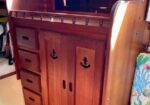 Polished wooden storage cabinet with drawers and double doors in a boat’s cabin.