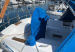 White sailboat cockpit with a blue cover and the shadow of the photographer, moored at a marina.