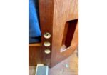 Close-up of a wooden door frame with a built-in pet door on the right and circular cutouts along the edge; blue fabric nearby.