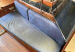 Blue upholstered bench seat with wooden frame and two back cushions in a cozy interior setting (likely dining area).