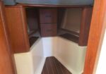 Under-berth storage area with two small drawers and shelves in a wooden boat cabin.