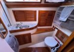 Small boat galley and head: compact bathroom with sink, wooden cabinets, and a toilet, towels on racks above.