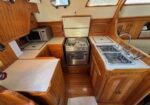 Wood-paneled boat galley with a compact stove/oven, double sink, microwave, and counter space.