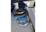 Blue braided rope wrapped around a silver boat winch on a textured deck surface.