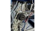 Close-up of a sailboat winch with coiled braided lines wrapped around it, part of the rigging on deck