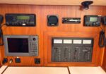 Navigation panel on a wooden boat dashboard with radios, gauges, and a control panel on the right side.