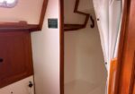 Wooden boat cabin interior with a closed cabinet on the left and an open closet area on the right, separated by a white curtain.