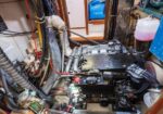 Diesel engine in a boat’s engine compartment with hoses, wiring, and a pink coolant reservoir in the background.