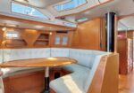 Wood-paneled boat interior with a U-shaped cream sofa around a polished wooden dining table.