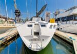 White sailboat docked at a marina, stern facing the camera, 'SAN FRANCISCO CA' on the hull, with masts and neighboring yachts nearby under a blue sky.