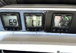 Three Raymarine boat gauges on a metal dashboard: left shows depth at 6.9 ft, center shows speed over ground around 0.1, right is an analog RPM gauge with a green-to-red arc.