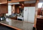 Boat galley with granite counter, wooden cabinets, fridge, microwave, and stove on a sailboat interior