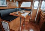 Wood-paneled boat cabin with a rectangular table and black bench seating; a snack tray sits on the table.