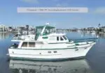 Pompano, a 1988 49' semi-displacement hull trawler yacht, white with green trim, docked in a calm marina.