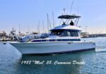 Motor yacht in a marina with two people on the flybridge; hull inscription reads 1988 'Med' 38, Cummins Diesels.
