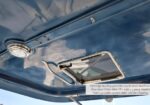 Underside of a blue boat roof with a small rectangular hinged hatch and a circular dome light nearby.