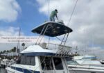 Man on the upper deck of a white yacht at a marina, working on a hardtop hatch; overlay reads “Hardtop hatch provides easy access for cleaning and service.”