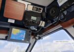 Boat cockpit electronics: GPS/chart plotter, VHF radio, and microphone on a wood panel.