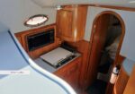 Compact boat galley with wooden cabinets, microwave, and stovetop; doorway to a cabin beyond.