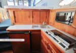 Wooden boat galley with a double sink, stove, and microwave; ample storage cabinets line the counter, caption reads: 'Galley has good amount of storage...'