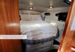 Owner's cabin with a large bed, plush white bedding, built-in storage drawers beneath, and two hanging lockers.