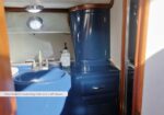 Blue compact boat head with round sink, chrome faucet, soap dispenser, and a tall blue cabinet above storage drawers.