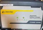 Cristec automatic battery charger mounted in a vehicle, with green status indicator lights and a 12V/40A label; a small note about batteries replaced in 2024 is visible on top edge.