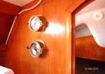 Wooden panel with two brass-encased round gauges on a boat interior surface