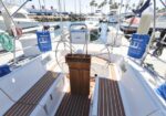 Sailboat cockpit with a wooden helm pedestal and steering wheel, teak deck, moored at a marina
