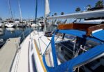 View from the deck of a sailboat in a marina, with other boats, masts, and calm water in the background.