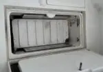 Open freezer drawer showing a metal ice tray inside a white refrigerator compartment.
