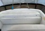 White ribbed boat cockpit seating with a curved backrest, cushioned benches, and a tinted window/windshield in the background.