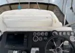 Helm of a boat with a steering wheel, instrument gauges, and a navigation screen on the left side.