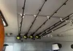 Overhead rod holders with six fishing rods secured to the ceiling of a vehicle or boat cabin.