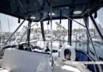 View from the boat's flybridge cockpit toward the marina, with white seating and steering wheel visible.