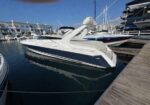 White and navy motor yacht moored at a marina with surrounding boats and a wooden pier on a sunny day.