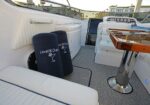 White yacht deck seating area with navy cushions bearing a Level III logo and a wooden pedestal table nearby.