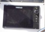 Marine navigation display by Simrad mounted on a boat helm, with control buttons on the right side.