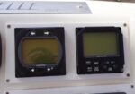 Two SIMRAD navigation screens side by side on a boat panel; left RS15, right AP16, with a faint reflection on the left display