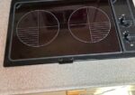 Double-burner electric hot plate on a countertop with control knobs on the right side.